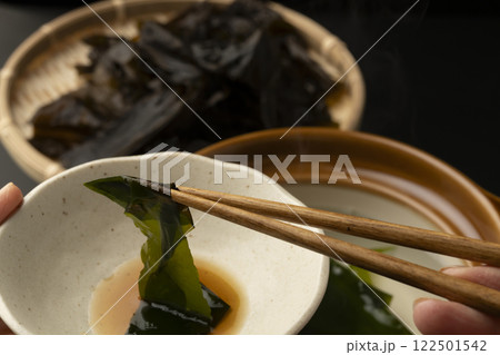 生わかめをしゃぶしゃぶで食べる　箸で生わかめを持ち上げる 122501542