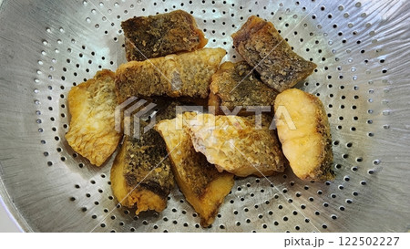 Crispy Golden Fried Fish Pieces in a Metal Strainer Bowl 122502227