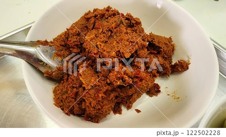 Curry paste for Thai cooking. Spicy chili paste in white bowl on stainless steel surface. 122502228
