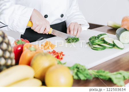 Chef hands preparing and cutting vegetables, Close up of a woman chef cutting vegetables, Hands of female chef cutting vegetables Chef hands preparing and cutting vegetables, Close up of a woman chef cutting vegetables, Hands of female chef cutting vegetables 122503634