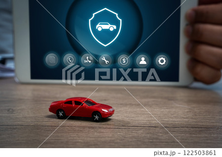 A small red toy car is on a wooden tableCar protection and safety assurance concept. 122503861