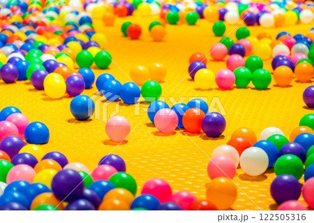 A vibrant scene of colorful plastic balls scattered across a bright yellow play surface. A vibrant scene of colorful plastic balls scattered across a bright yellow play surface. 122505316