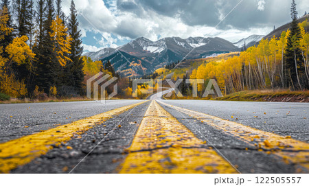 Low angle view of asphalt road with yellow lines. Highway with mountains and autumn forest. 122505557