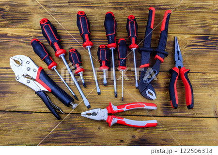 Set of different pliers and screwdrivers on wooden background. Top view Set of different pliers and screwdrivers on wooden background. Top view 122506318