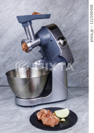 Electric eat grinder and fresh meat on kitchen table. Preparation of minced meat 122506406