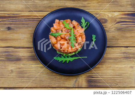 Salmon tartare with avocado and arugula on wooden table. Top view Salmon tartare with avocado and arugula on wooden table. Top view 122506407