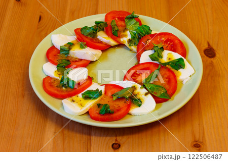 Italian caprese salad with tomatoes, mozzarella cheese and basil on a wooden table Italian caprese salad with tomatoes, mozzarella cheese and basil on a wooden table 122506487
