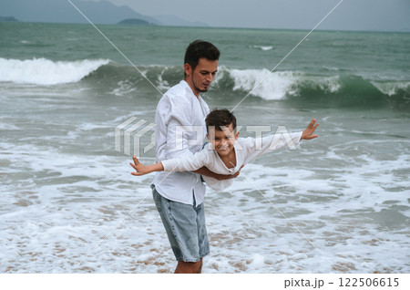 happy father dad with child boy son playing on beach by the sea in summer on vacation 122506615