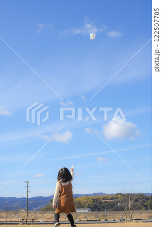 青空の下で凧揚げをする女の子 122507705