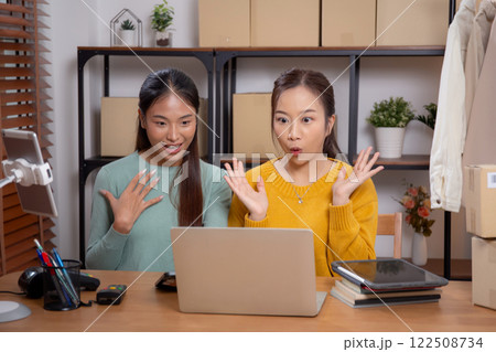 Two young asian woman using laptop computer for live streaming of store in office with success. Two young asian woman using laptop computer for live streaming of store in office with success. 122508734