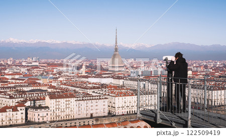 A tourist looks through a sightseeing binoculars on city of Turin A tourist looks through a sightseeing binoculars on city of Turin 122509419