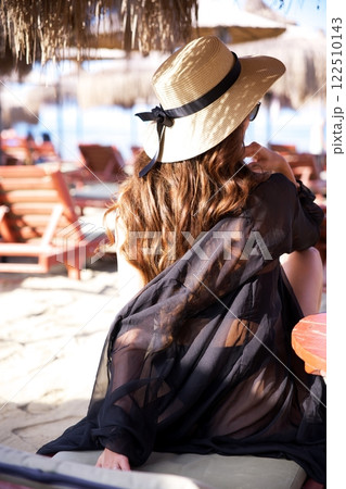 Woman in sun hat relaxing at beach resort Woman in sun hat relaxing at beach resort 122510143