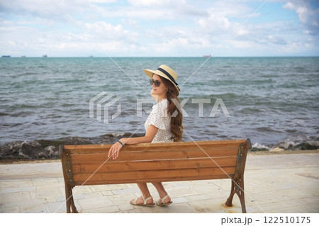 Woman in sun hat relaxing by the ocean 122510175