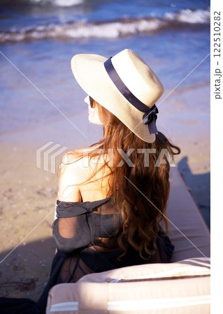 Woman in sun hat relaxing by the ocean waves  122510282