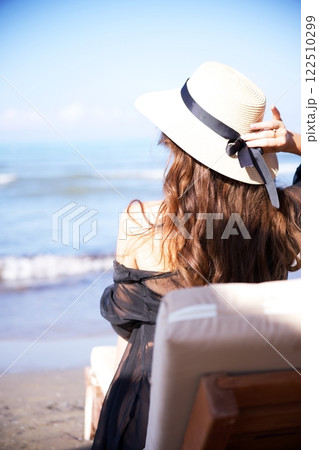 Woman in sun hat enjoying ocean breeze by beach  122510299