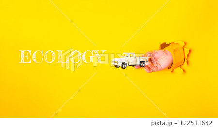 Hand holding a toy truck in front of the word Ecology Hand holding a toy truck in front of the word Ecology 122511632