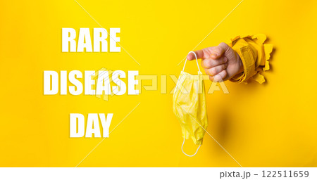 Person holding a yellow mask with the words Rare Disease Day written below Person holding a yellow mask with the words Rare Disease Day written below 122511659
