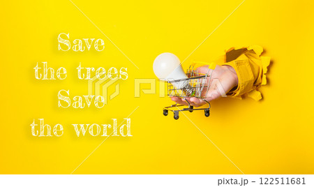 Person holding a light bulb in a shopping cart with the words Save the Trees Person holding a light bulb in a shopping cart with the words Save the Trees 122511681