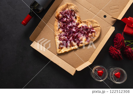 Valentine's Day Heart shaped sweet pizza with pineapple in cardboard paper box on black background. Romantic dinner with red wine and gift. Fast food delivery. View from above. Copy space. Valentine's Day Heart shaped sweet pizza with pineapple in cardboard paper box on black background. Romantic dinner with red wine and gift. Fast food delivery. View from above. Copy space. 122512308