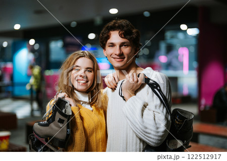 Young couple enjoys ice skating at a rink during winter evening 122512917