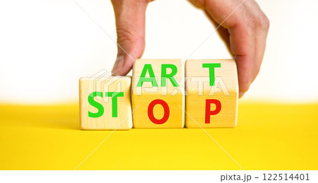 Start or stop symbol. Concept words Start or Stop on beautiful wooden block. Beautiful yellow table white background. Businessman hand. Business start or stop concept. Copy space. Start or stop symbol. Concept words Start or Stop on beautiful wooden block. Beautiful yellow table white background. Businessman hand. Business start or stop concept. Copy space. 122514401