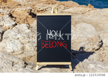 Belonging and you belong symbol. Concept words You belong on beautiful yellow chalk blackboard. Beautiful stone beach blue sky background. Business belonging and you belong concept. Copy space. Belonging and you belong symbol. Concept words You belong on beautiful yellow chalk blackboard. Beautiful stone beach blue sky background. Business belonging and you belong concept. Copy space. 122514506