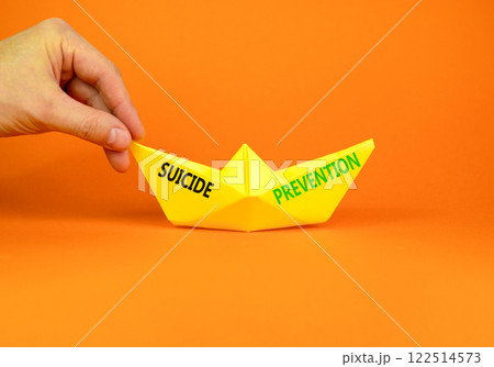 Suicide prevention symbol. Concept words Suicide prevention on beautiful yellow paper boat. Beautiful orange background. Psychologist hand. Psychological and suicide prevention concept. Copy space. Suicide prevention symbol. Concept words Suicide prevention on beautiful yellow paper boat. Beautiful orange background. Psychologist hand. Psychological and suicide prevention concept. Copy space. 122514573