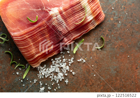 Sliced prosciutto and rosemary on a brown rusty background. 122516522