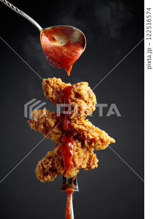 Fried chicken with ketchup on a fork. Fried chicken with ketchup on a fork. 122516574