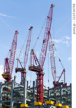Low-angle view of cranes and steel structures of building construction with a blue sky background in Taiwan. Low-angle view of cranes and steel structures of building construction with a blue sky background in Taiwan. 122516708