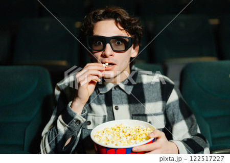 Young man enjoying popcorn while watching a movie in a theater 122517227