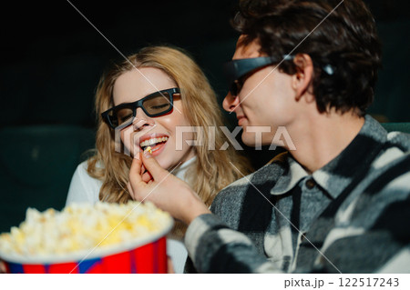 Couple enjoying popcorn while watching a film in 3D glasses at the cinema 122517243