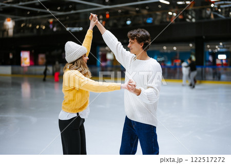 Couple enjoying ice skating while laughing and dancing together indoors 122517272