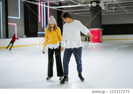 Young couple enjoying ice skating together in a modern indoor rink 122517273