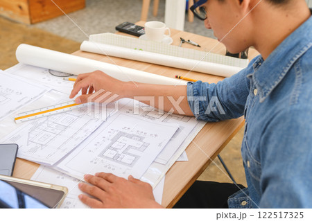 Young architect sketching house plans on a work desk in a modern office 122517325
