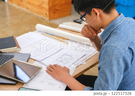 Young architect sketching house plans on a work desk in a modern office 122517326