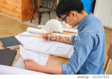 Young architect sketching house plans on a work desk in a modern office 122517331