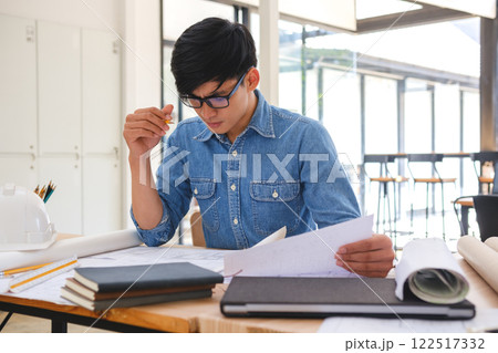 Young architect sketching house plans on a work desk in a modern office 122517332