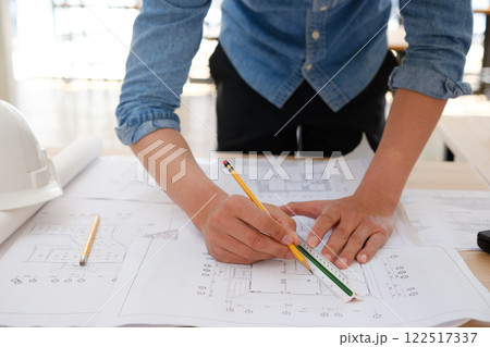 Young architect sketching house plans on a work desk in a modern office Young architect sketching house plans on a work desk in a modern office 122517337
