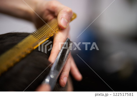 Haircut taking place at a barbershop with tools in use for styling Haircut taking place at a barbershop with tools in use for styling 122517581
