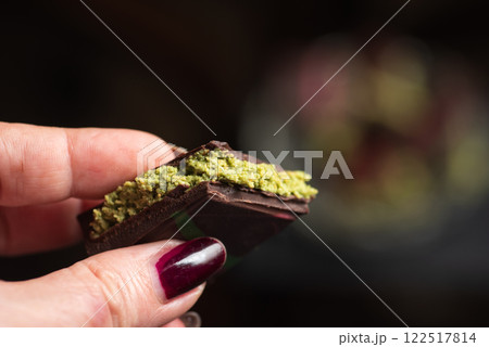 Female Hand Holding Delicious Dark Chocolate with Pistachio Filling. Viral dubai chocolate Female Hand Holding Delicious Dark Chocolate with Pistachio Filling. Viral dubai chocolate 122517814