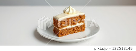 Moist spiced cake slice topped with creamy frosting on a simple white plate in a bright setting 122518149