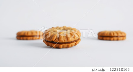 Delicious golden cookies arranged on a white surface showcasing rich chocolate filling in the center 122518163