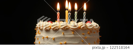 Celebrating a special birthday with a cake topped by five lit candles and colorful decorations 122518164