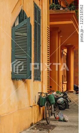 This is a charming urban scene featuring a bicycle positioned against a vibrant orange wall 122518562