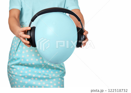 Female hand holding blue balloon with headphones on white background Female hand holding blue balloon with headphones on white background 122518732