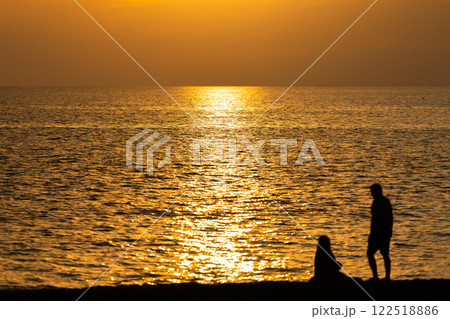 Golden Hour Romance: Lovers Embraced by the Ocean Breeze 122518886