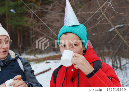Friends celebrate winter with treats and warm drinks in a snowy forest during a festive outing Friends celebrate winter with treats and warm drinks in a snowy forest during a festive outing 122519369