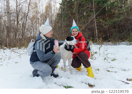 Two friends wearing colorful winter attire and party hats joyfully play in the snow Two friends wearing colorful winter attire and party hats joyfully play in the snow 122519570
