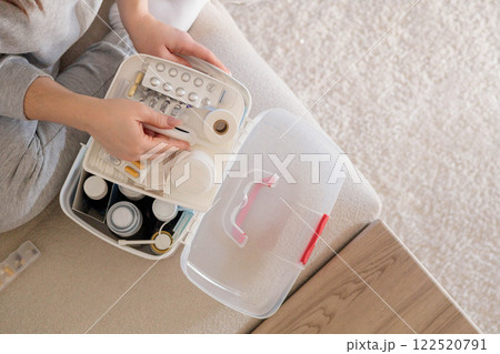 Closeup female hand neatly placing medicament at domestic first aid kit top view. 122520791